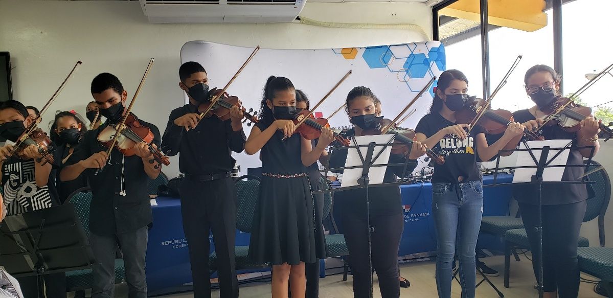 Niños y niñas tocando instrumentos de cuerda.